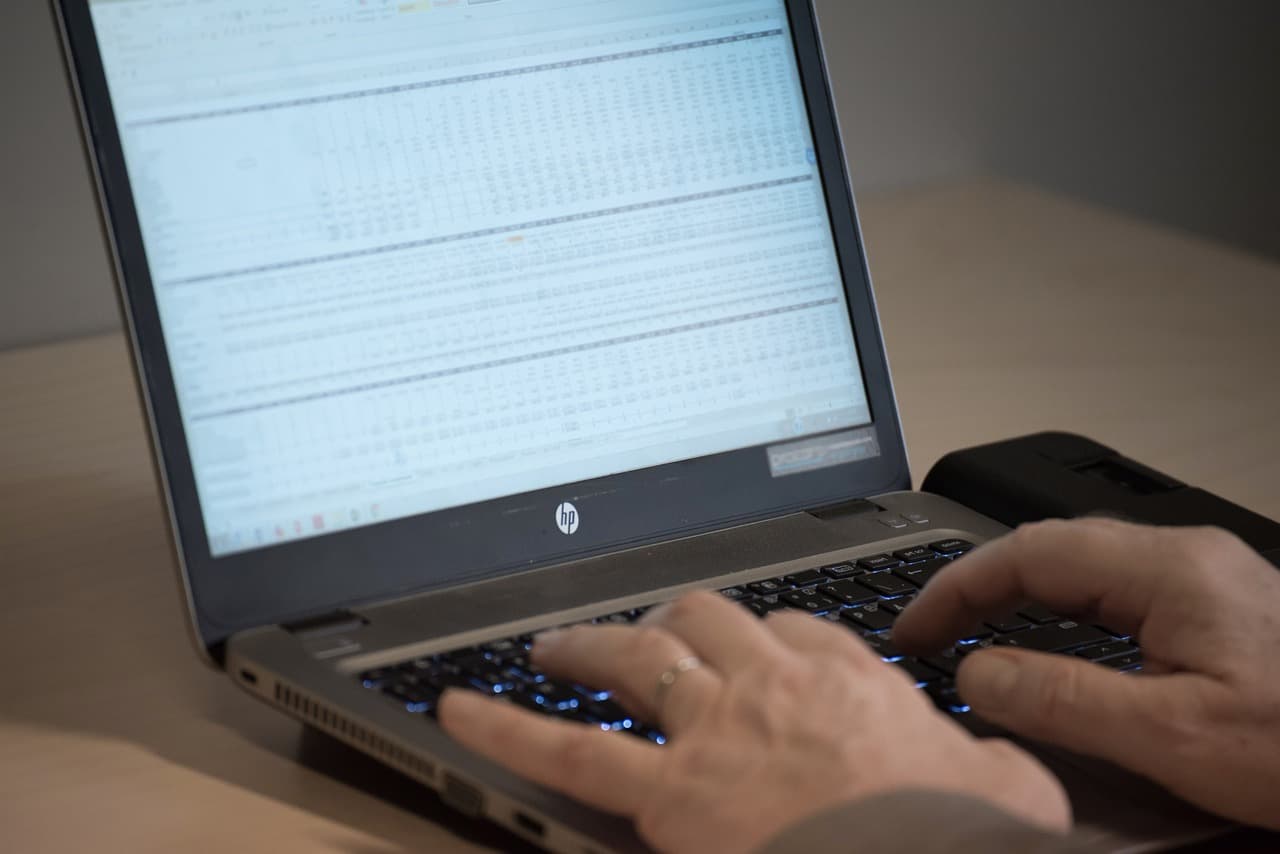 Ett städat skrivbord med en laptop som visar ett kalkylblad med en finansiell modell, ett anteckningsblock och en kaffekopp i ett modernt svenskt kontor